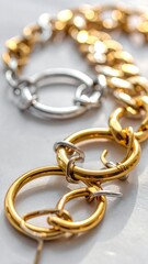 Close-up of shiny gold and silver linked jewelry on a light surface