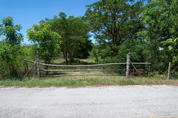 A temporary bamboo gate blocks off the dirt road from the main road.