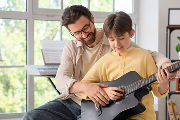 Fototapeta premium Private music teacher giving guitar lessons to boy in room