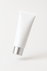 Floating white cosmetic tube with silver cap isolated on clean background, minimal mockup design for skincare, lotion, sunscreen, cream, or cosmetic branding, clean studio lighting