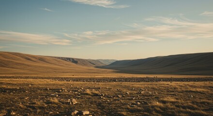 A vast, golden-toned plain stretches between gently sloping hills under a tranquil, partly cloudy sky.