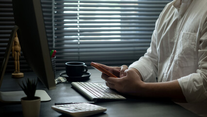 Businessman is using a smartphone while sitting at his desk