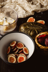 Rustic homemade fig galette on parchment paper. A dark and moody food photography still life with low key lighting, served on a vintage wooden table with a wicker basket and lace.