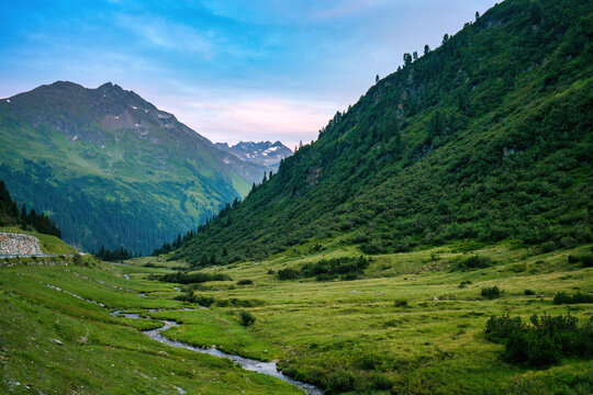 Winding stream flowing through green mountain valley in Austria