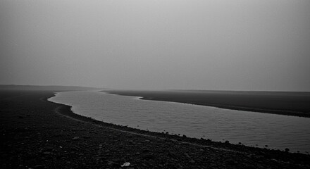 A meandering river winds through a vast, misty landscape, creating a serene and minimalist scene.