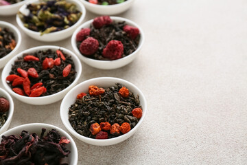 Bowls with different fruit tea on light grunge background