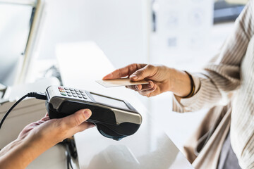 Customer making a payment using a credit card with contactless technology at a pos terminal. Transaction on a counter