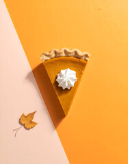 Slice of Pumpkin Pie with Whipped Cream and Autumn Leaf.