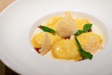 Ravioli in creamy cheese sauce with basil and parmesan crisps
