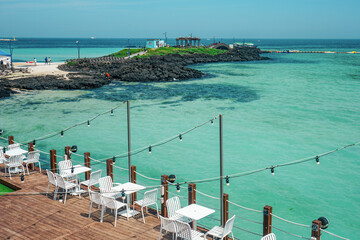 Jeju City, Jeju Island, South Korea - June 23 2025: Dining area at a seaside restaurant overlooks Hamdeok Beach