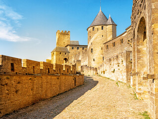 Medieval fortress walls and towers of Carcassonne at sunset, France. Old medieval walls of Carcassonne illuminated by purple sunset sky.