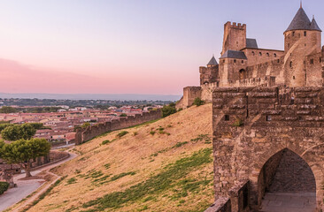 Medieval fortress walls and towers of Carcassonne at sunset, France. Old medieval walls of Carcassonne illuminated by purple sunset sky.