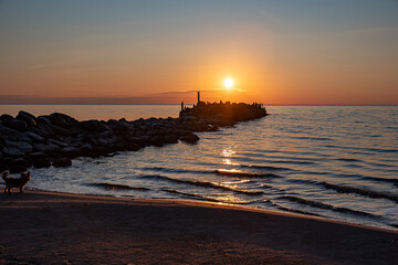 Magical sunset by the sea, old stone pier, the last rays of the sun reflected in the calm sea...