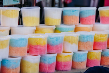 Colorful containers of cotton candy stacked on display at market or carnival