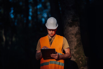 Forestry engineer taking notes on clipboard in forest at night