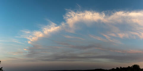 Vibrant clouds stretch across a clear blue sky highlighting the calm of dusk over a serene landscape without urban interruptions