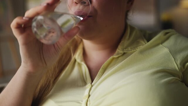 Smiling young woman drinking water and taking medication, vitamins for health