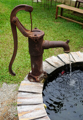 Vintage rusty hand pump and well decoration at garden
