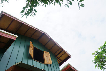 Open window at house with tree trunk and sky background