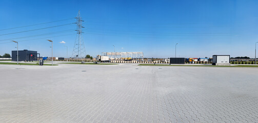 Industrial landscape with a clear blue sky and a large parking area.