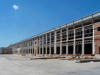 Construction site of a large industrial building under a clear blue sky.