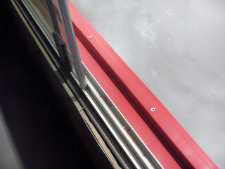Detail of a hockey rink's red boards and protective glass, angled view.