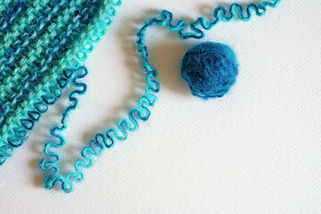 Unravelling green wool knitted garment on white background. Copy space