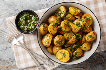 Roasted Potatoes with Chimichurri Sauce are packed with flavors closeup on the plate on the table. Horizontal top view from above