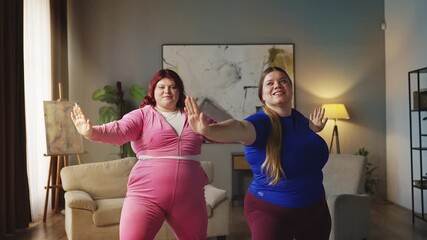 Happy plus size sisters doing yoga together at home, fitness and weight loss