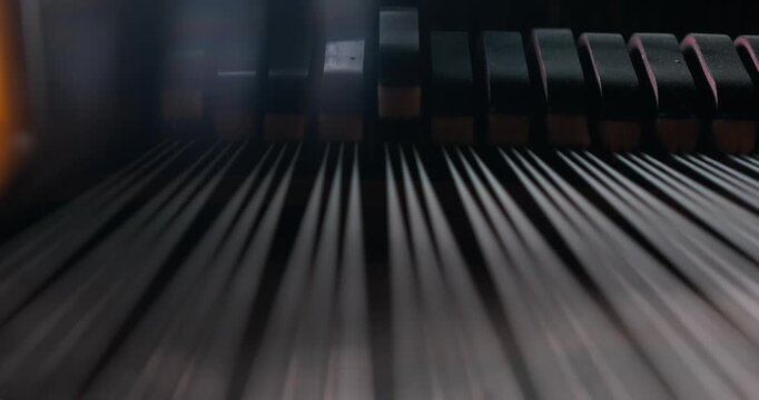 Dusty mechanical hammers striking grand piano strings in soft light