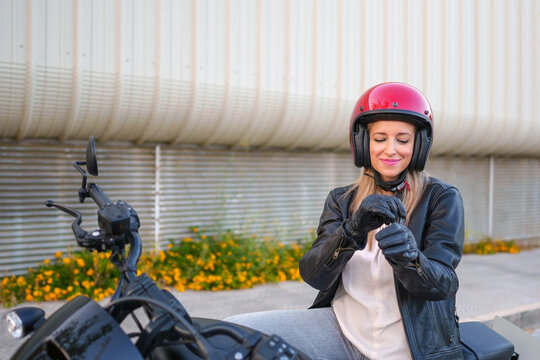 Biker with leather jacket adjusting glove on motorcycle outdoors