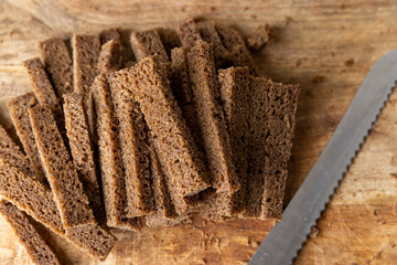 fresh black rye bread sliced for croutons on a board, pieces of fresh soft sliced bread made from rye flour , bread for frying in oil with spices
