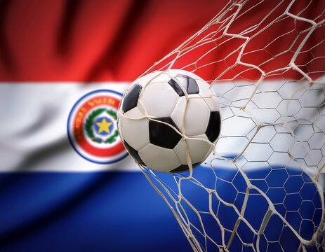 close-up of soccer ball with the goal net; blurred paraguay flag in the background