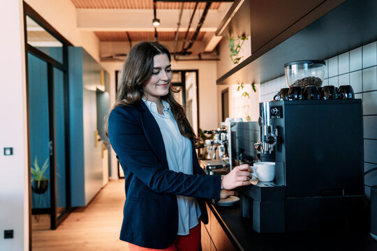 Businesswoman preparing coffee at office kitchen during break