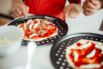 Mother and son preparing homemade pizza together in kitchen