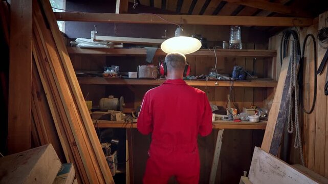 The master stands in his workshop under a swinging lamp.