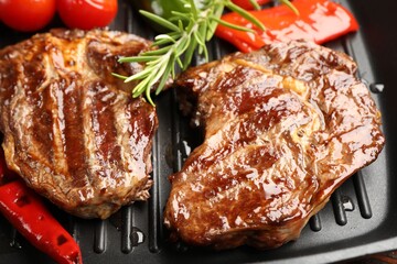 Grilled beef steaks, rosemary and vegetables on black pan, closeup