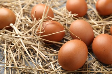 Raw chicken eggs and straw on table, closeup