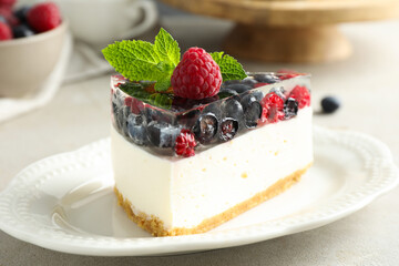 Piece of delicious cheesecake with berries and mint on light grey table, closeup