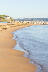 A calm, empty sandy beach with gentle waves lapping the shore in Santander, Spain. A concept of a...