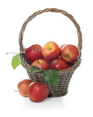 Fresh apples in wicker basket and green leaves isolated on white