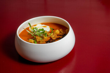 Gourmet tomato soup served in an elegant bowl, crafted by a top chef. Rich, vibrant red color, perfect lighting, fine dining presentation, and artistic culinary style.