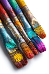 Obraz premium Macro shot of well-used artist paintbrushes covered in vivid, colorful paint against a white background, symbolizing creativity and art