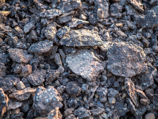 Close-up of milled recycled asphalt pieces used for road repair and construction material.