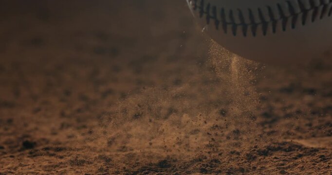 Macro cinematic shot of a baseball falling onto dry soil in ultra slow motion captured at 1000 fps.Dust and particles under dramatic lighting.Sport concept.