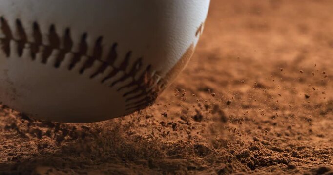 Macro cinematic shot of a baseball falling onto dry soil in ultra slow motion captured at 1000 fps.Dust and particles under dramatic lighting.Sport concept.