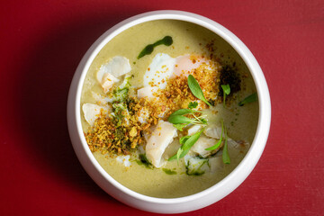 Traditional Portuguese codfish soup 'Açorda de Bacalhau', crafted by a chef, featuring bread, boiled egg, garlic, olive oil, and herbs in a gourmet presentation.