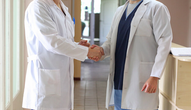 Close-up of two doctors shaking hands, favorable treatment prognosis. Medicine concept