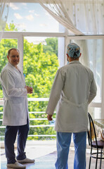 Two doctors on a break breathing air near an open window. Colleagues. Friendly relationships at work.