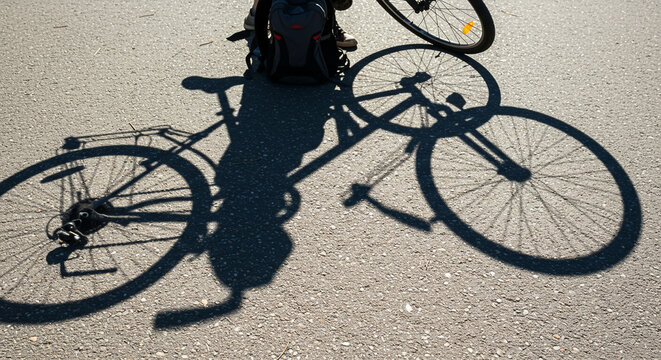 Silhouette of a bicycle shadow on the asphalt during a sunny day commute, symbolizing eco-friendly transport and an active lifestyle - Powered by Adobe